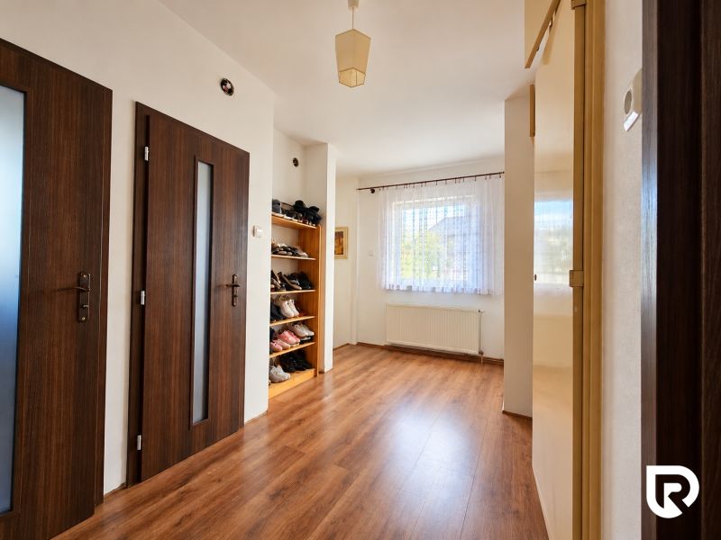 Interior of a family house with a wooden decor floor, doors, and a shoe rack.