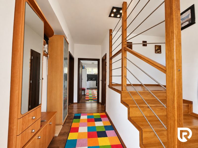 Interior of a family house with a staircase made of wood decor and a colorful carpet.