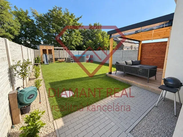 A landscaped garden of a family house in Čierna Voda, Čierna Voda, with a terrace and lawn.