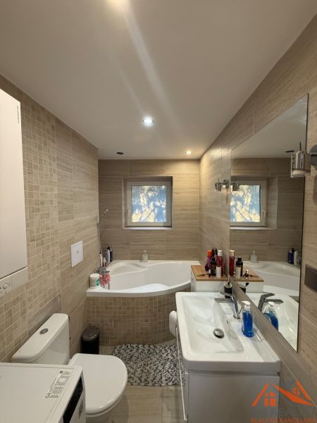 Bathroom in a 2-room apartment with a bathtub, sink, and washing machine, tiled with tiles.