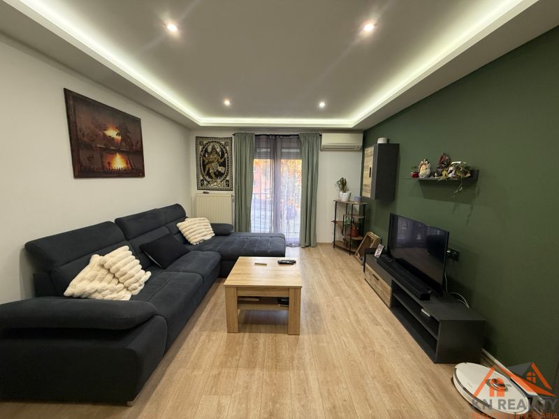 Living room in a two-room apartment with a wood-patterned floor and a sofa.