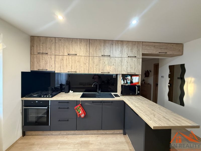 A kitchen in a 2-room apartment with black cabinets and a wooden decor floor.