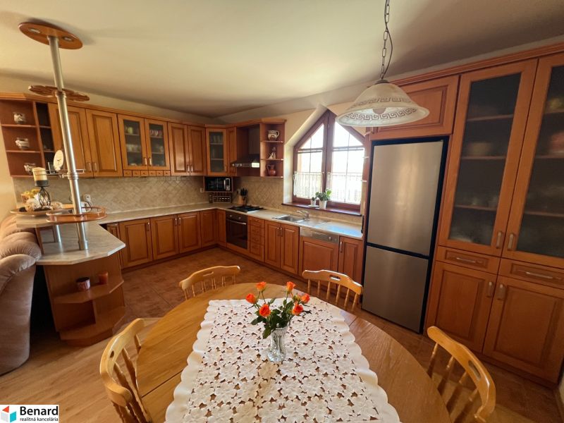 A family house kitchen with wooden furniture, a floor with a wooden design, and a dining table.