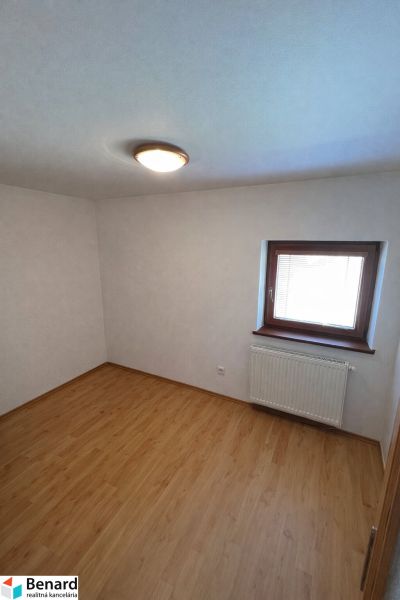 A room in a family house with a wooden decor floor and a window with a radiator.