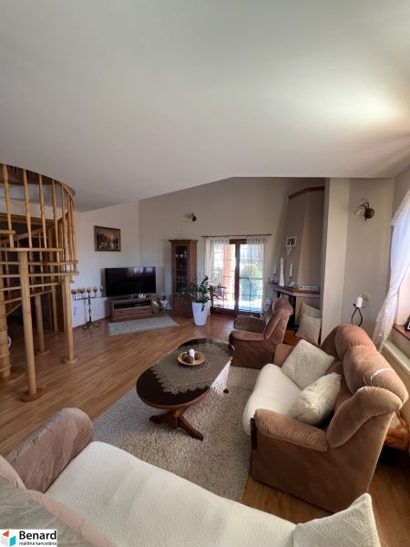 Living room in a family house with a comfortable couch, staircase, and wooden decor flooring.