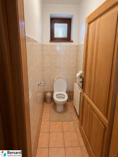 Bathroom interior of a family house with a toilet, window, and tiles.