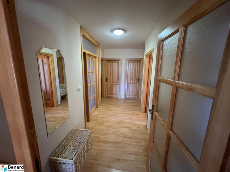 A hallway in a family house with a wooden decor floor and multiple doors.
