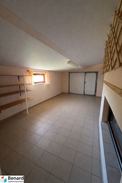 Interior of a family house with tiles, storage shelves, and a window with sheer curtains.