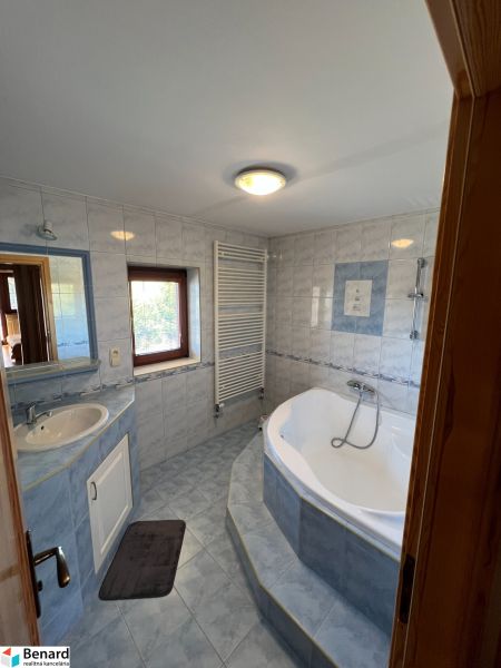 A bathroom with a bathtub and a sink in a family house, tiled walls.