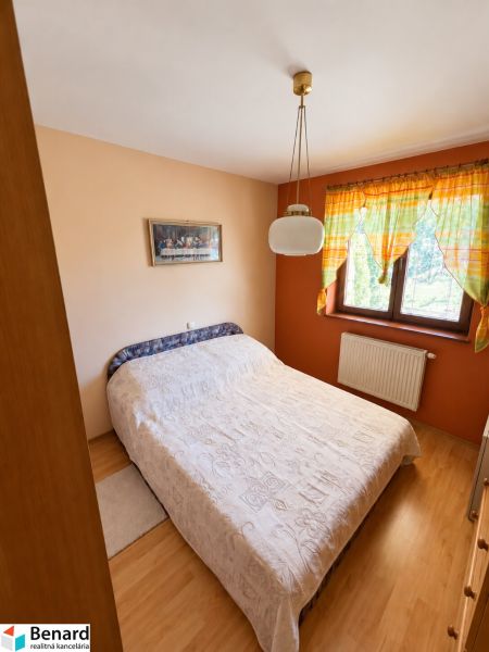Bedroom in a family house with a bed, curtains, and a wooden decor floor.