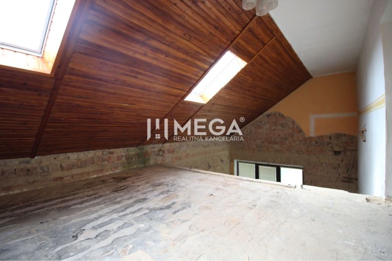The attic of a family house with wooden roof windows, a brick wall, and light tubes in the roof.