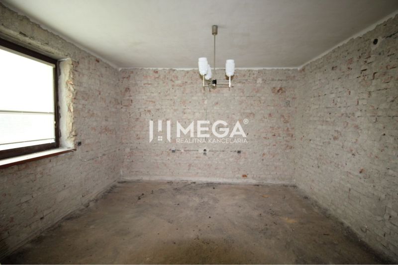 Room in a family house with exposed brick walls and a pendant light.