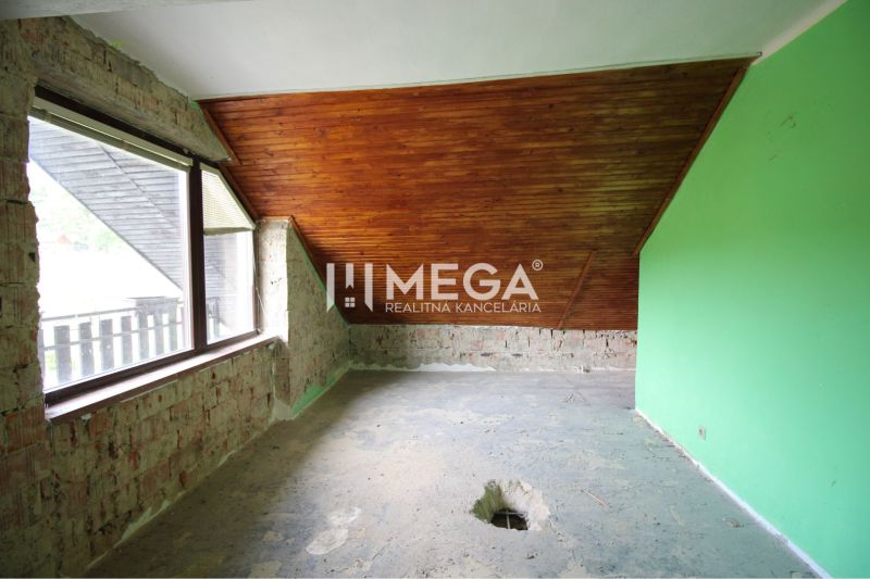 A room in a family house with a wooden ceiling and exposed bricks.