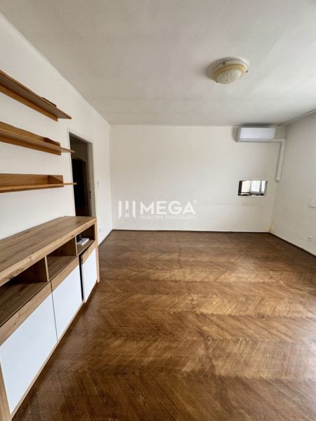 A room in a 3-room apartment with a wooden decor floor and wall shelves.