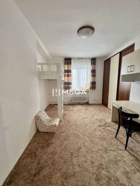 A room with a carpet, a bunk bed, a desk, and a chair in a three-room apartment.