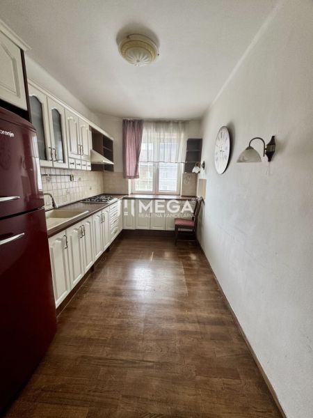 A kitchen in a 3-room apartment with a wooden decor floor, white furniture, red refrigerator.