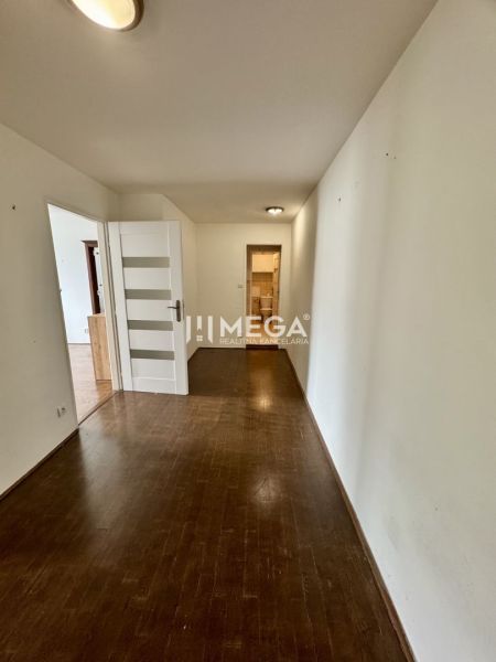 A hallway in a 3-room apartment with white doors and a floor with a wooden design.