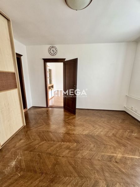 A room in a 3-bedroom apartment with a wood-patterned floor and open doors.
