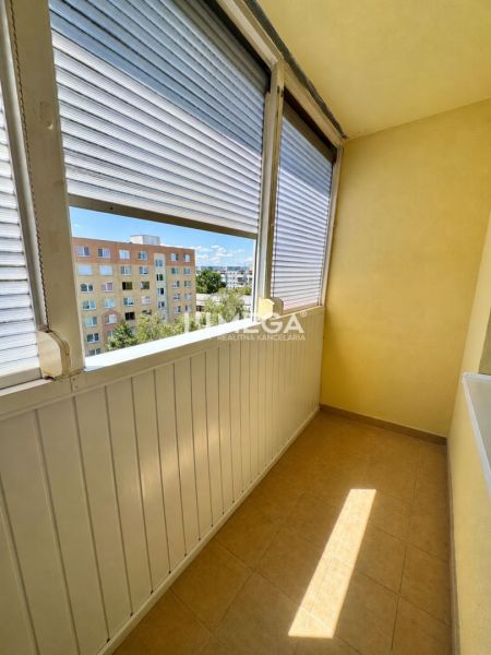 A glazed balcony with a view of apartment buildings, part of a studio apartment.