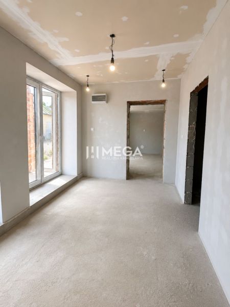 Interior of a family house with a concrete floor, plastered walls, and large windows.