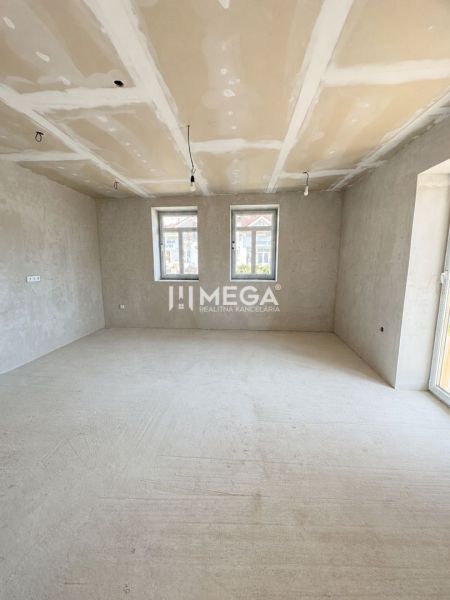 A spacious room in a family house with large windows and a concrete floor.