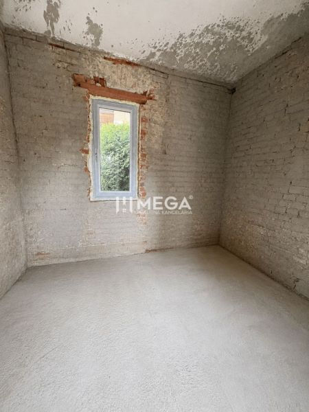A raw room in a family house with a gray floor and exposed bricks.