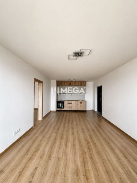 Living room in a 3-room apartment with a wooden decor floor and a kitchen unit.
