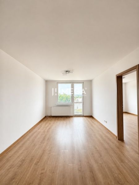 Spacious living room with wood-patterned flooring in a three-room apartment.