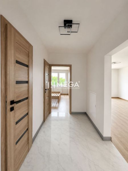 A hallway in a 3-room apartment with wooden doors and a floor with a wooden decor.