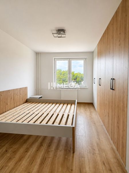 A bedroom in a three-room apartment with a wooden decor floor and a built-in wardrobe.