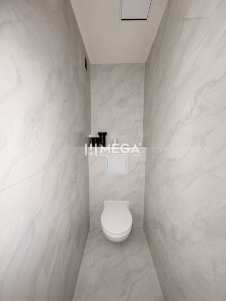 A toilet with a minimalist design and light ceramic tiles in a 3-room apartment.