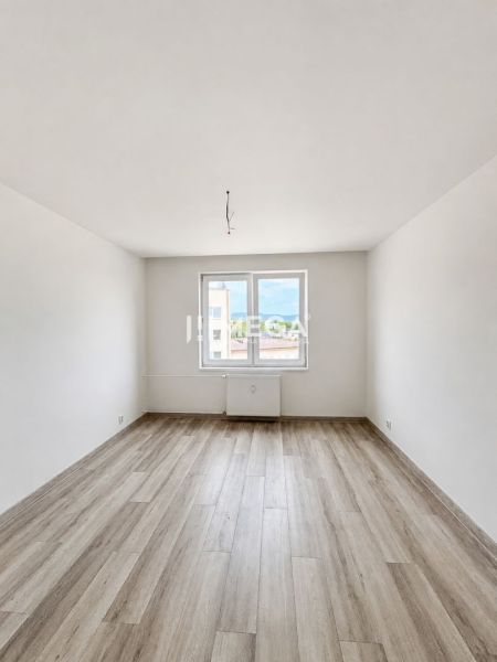 A bright empty space with white walls and a wooden decor floor in a 2-room apartment.