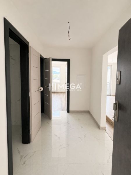 A hallway of a 2-room apartment with a wooden decor floor and white walls.