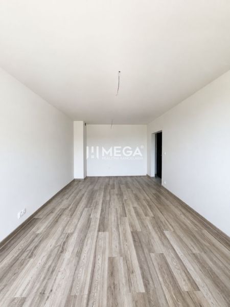 A spacious room with a wooden decor floor in a 2-room apartment.