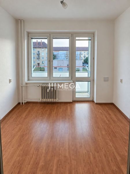 A room in a 2-room apartment with a wooden decor floor and a large window.
