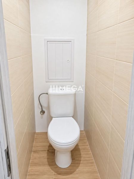 Bathroom in a 2-room apartment with tiles and a wood-patterned floor.