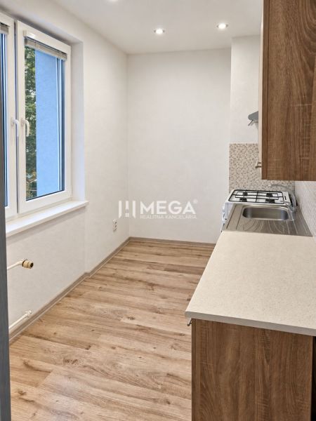 A kitchen in a 2-room apartment with a wooden decor floor and a window.