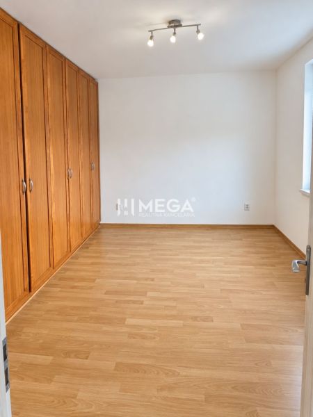 A bedroom in a 2-room apartment with a wooden decor floor and built-in wardrobes.