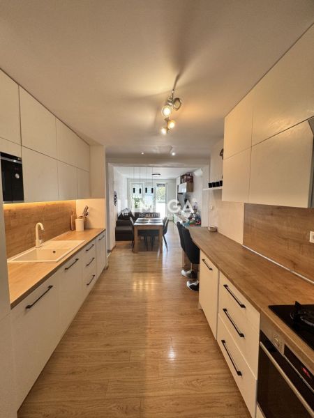 A kitchen in a 3-room apartment with a wood-decor floor and white cabinets.