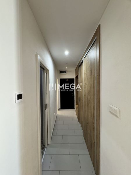 A hallway in a 3-room apartment with white walls and a wooden decor floor.