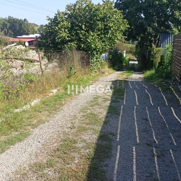 A gravel road leads through green residential areas on a street in Humenné.