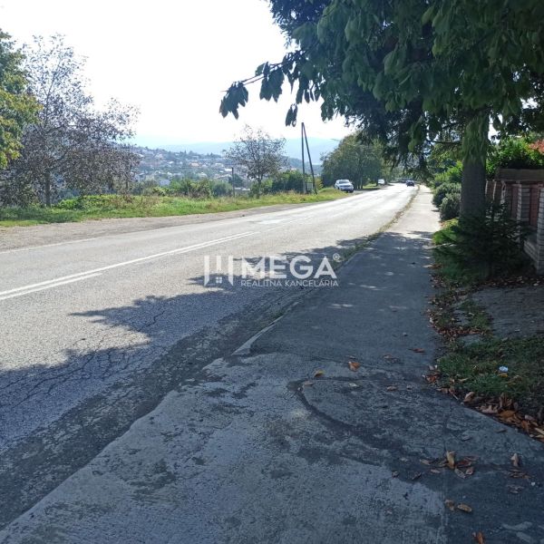 Street view in Humenné on residential plots, with a road and a sidewalk.