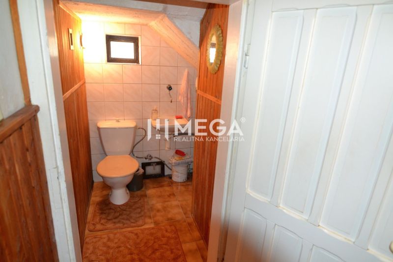 A toilet with tiles and a small window in a family house.