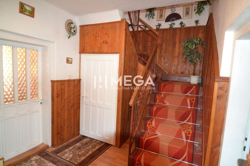 A staircase in a family house with wooden paneling and a red carpet.
