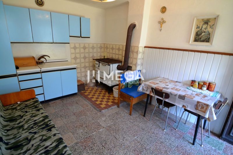 A kitchen in a family house with an old tiled stove and blue kitchen cabinets.