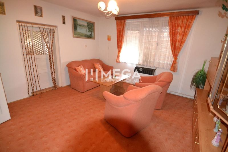 Living room in a family house with orange furniture and carpet, curtains on the windows.