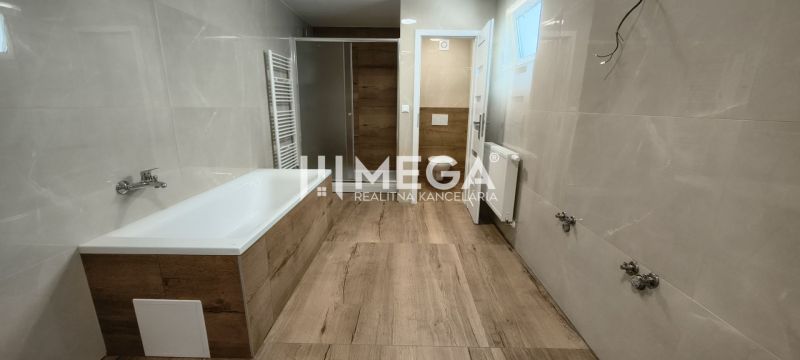 A bathroom with a bathtub, shower, and floor with a wooden decor in a 4-room apartment.