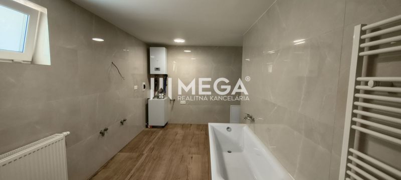 A bathroom with light tiles, a bathtub, and a floor with a wood decor in a 4-room apartment.