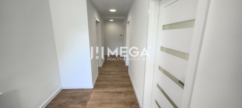 A hallway in a 4-room apartment with white walls and a floor with a wood decor.