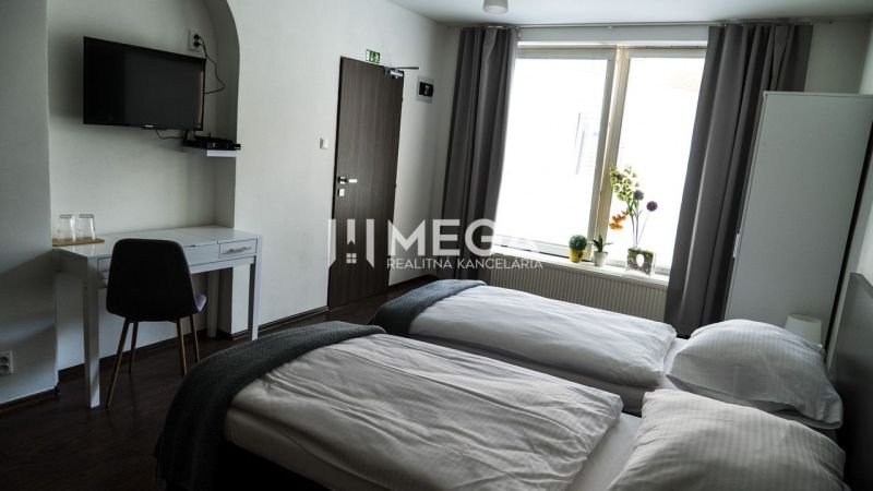 A hotel room with two beds, a television, and a floor with a wooden decor.